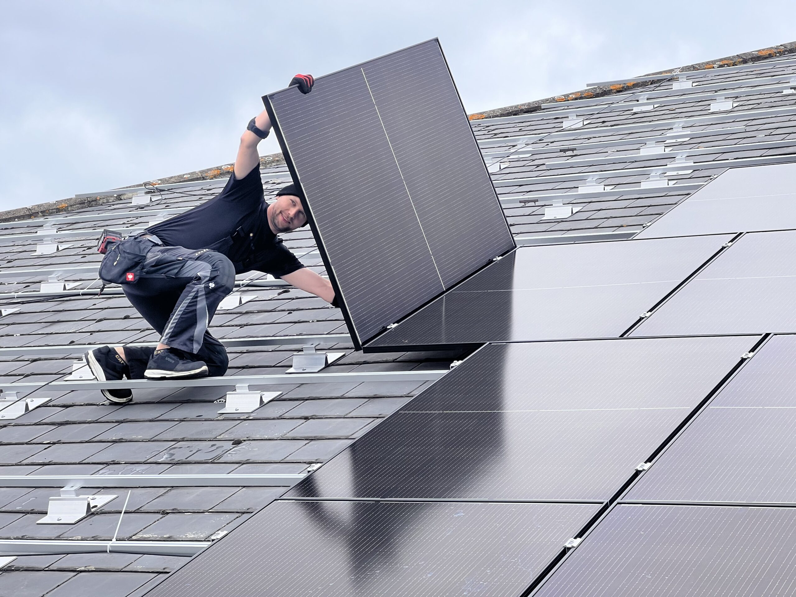 Solar panel installer fitting solar panels to a pitched roof